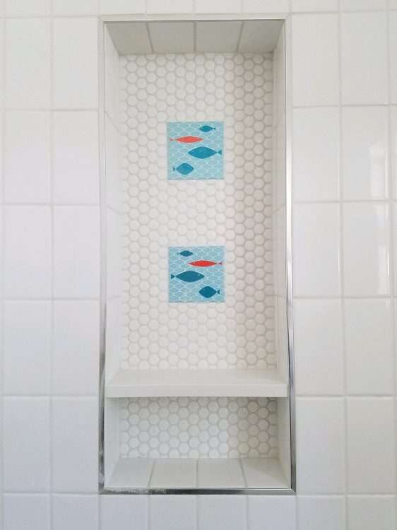 Two fish tile from our decorative ceramic tile line accent this shower niche.